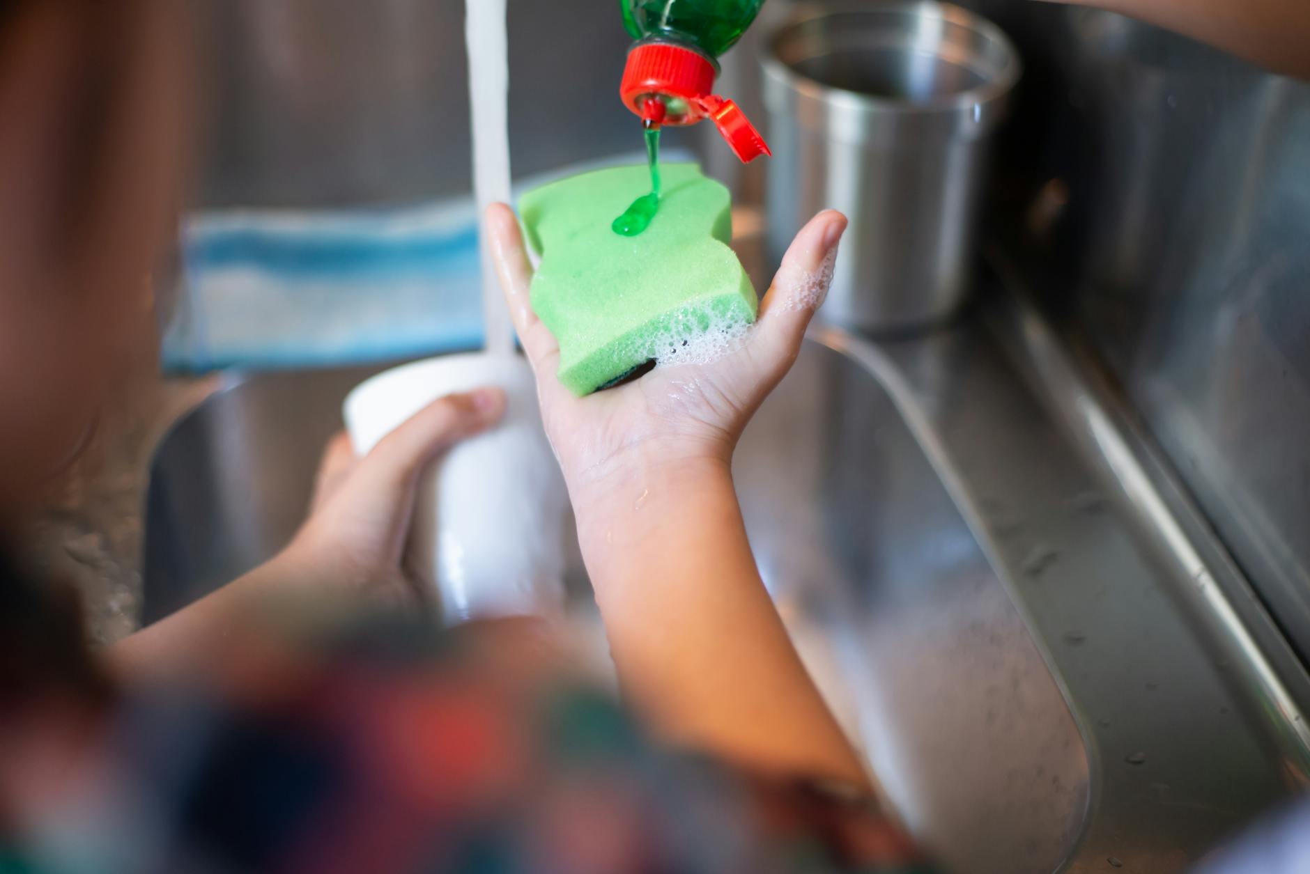 a person pouring liquid soap on a sponge